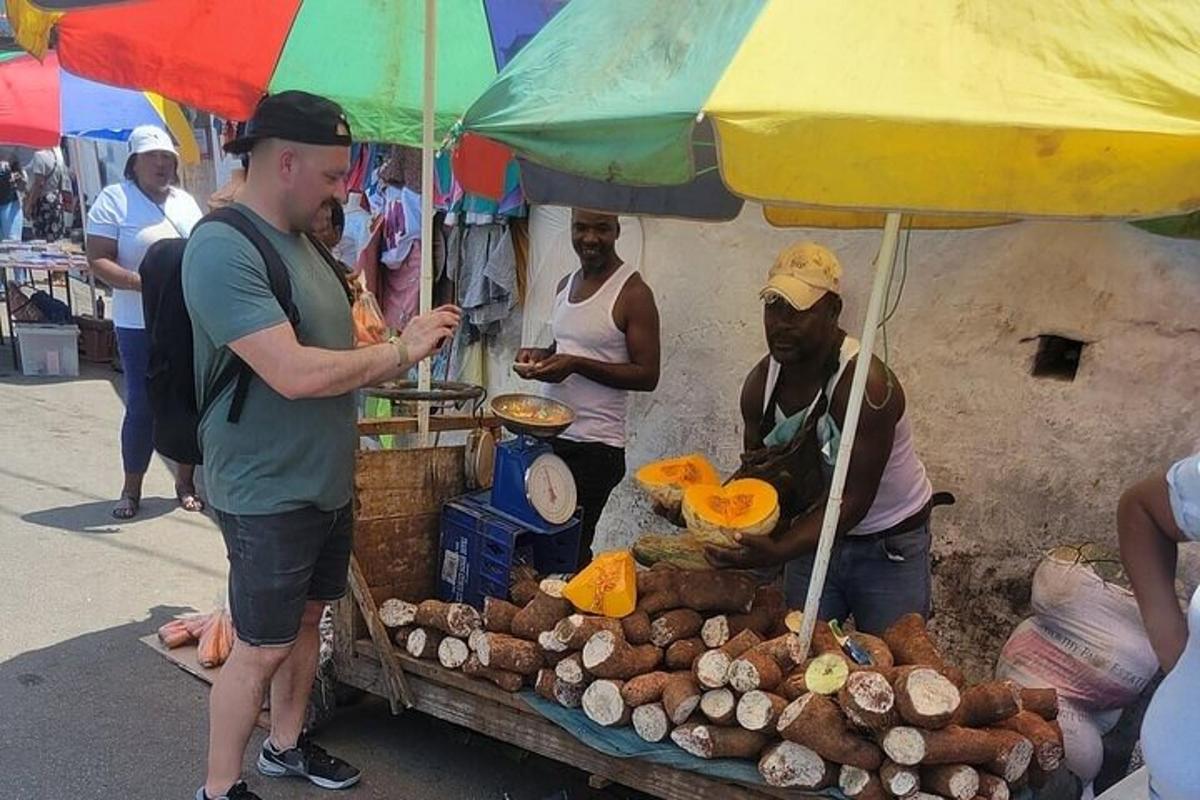 a man standing in front of a food stand under an umbrella