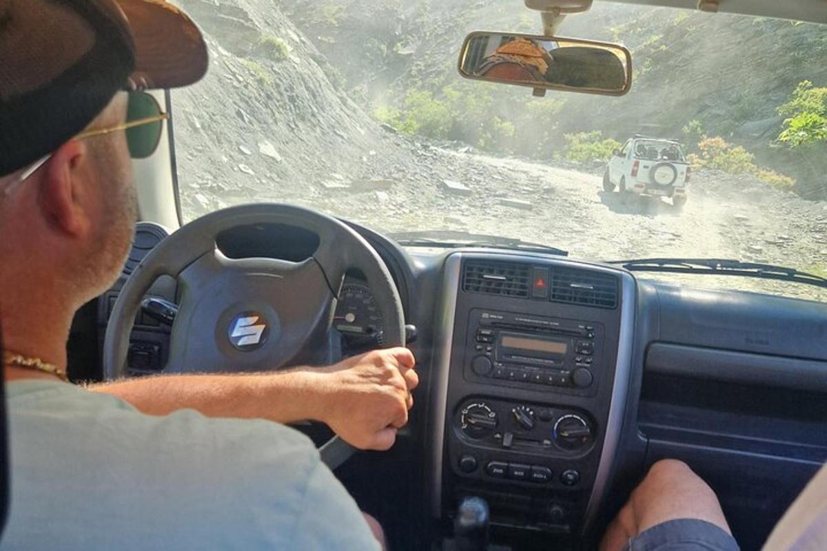 чоловік керує автомобілем по ґрунтовій дорозі