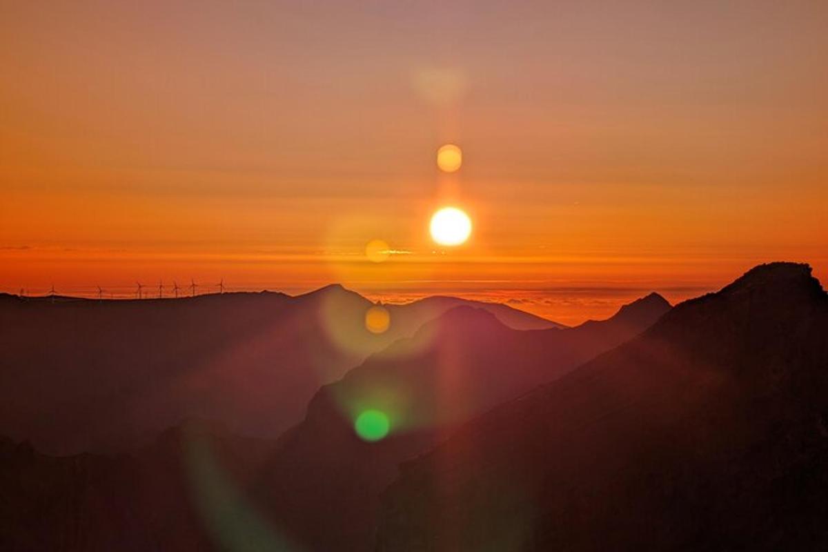 a sunset over the mountains with the sun in the sky