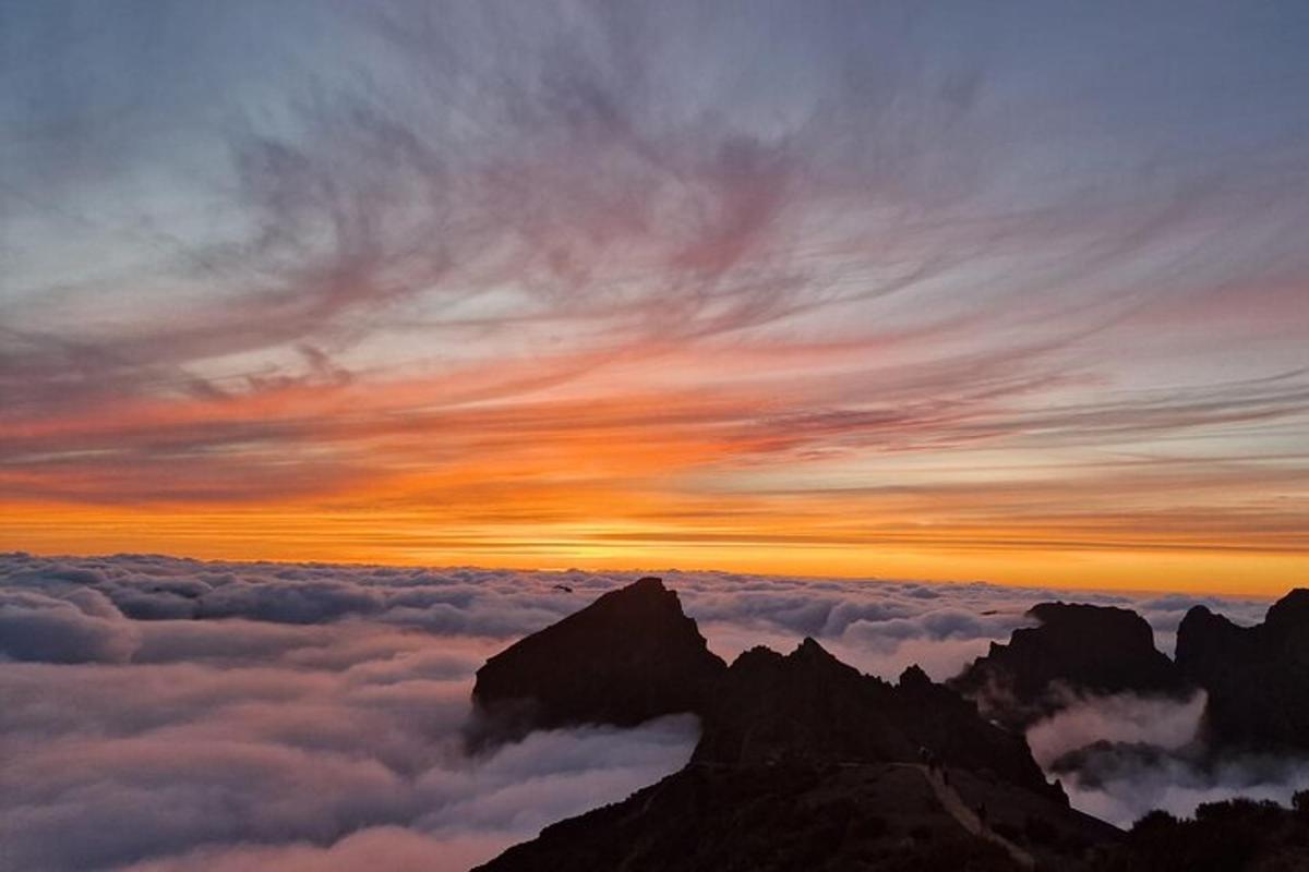 a sunset at the top of a mountain with clouds