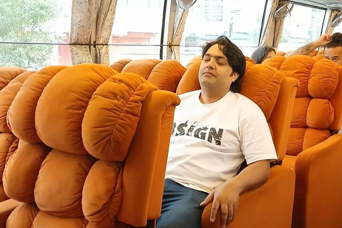 一名男子坐在公交车上的橙色座位上