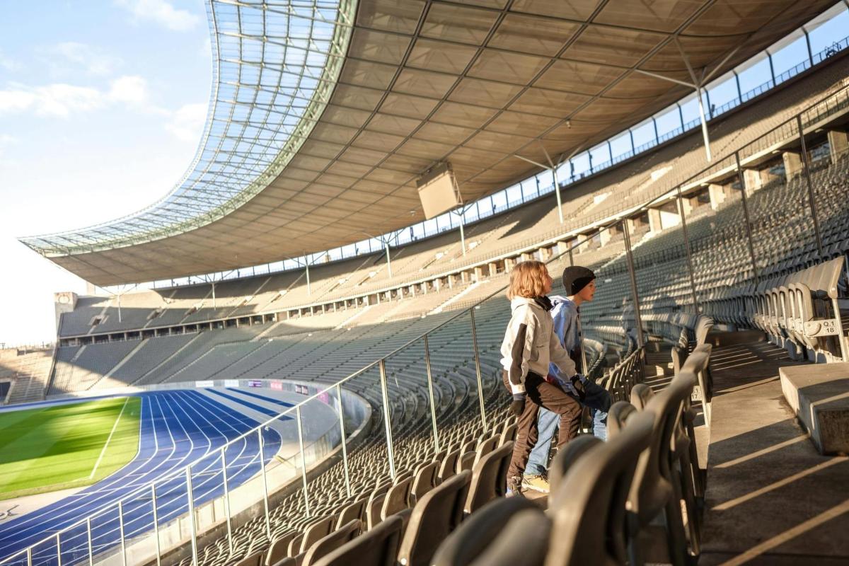 Dos personas de pie en un estadio con un tren.