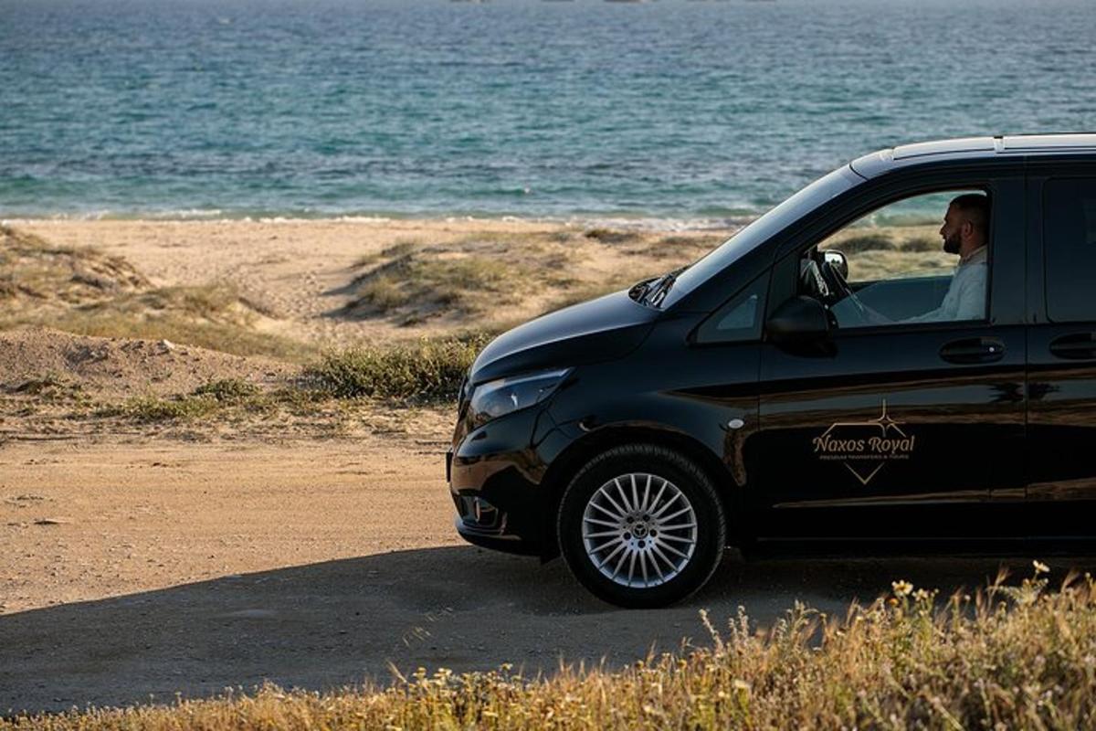 a man driving a black car on the beach
