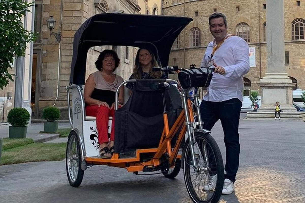 vīrietis stumj velosipēdu, un divas sievietes karietē