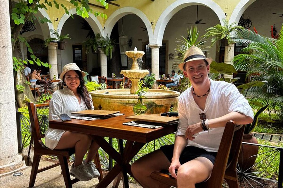 Un hombre y una mujer sentados en una mesa en un patio.