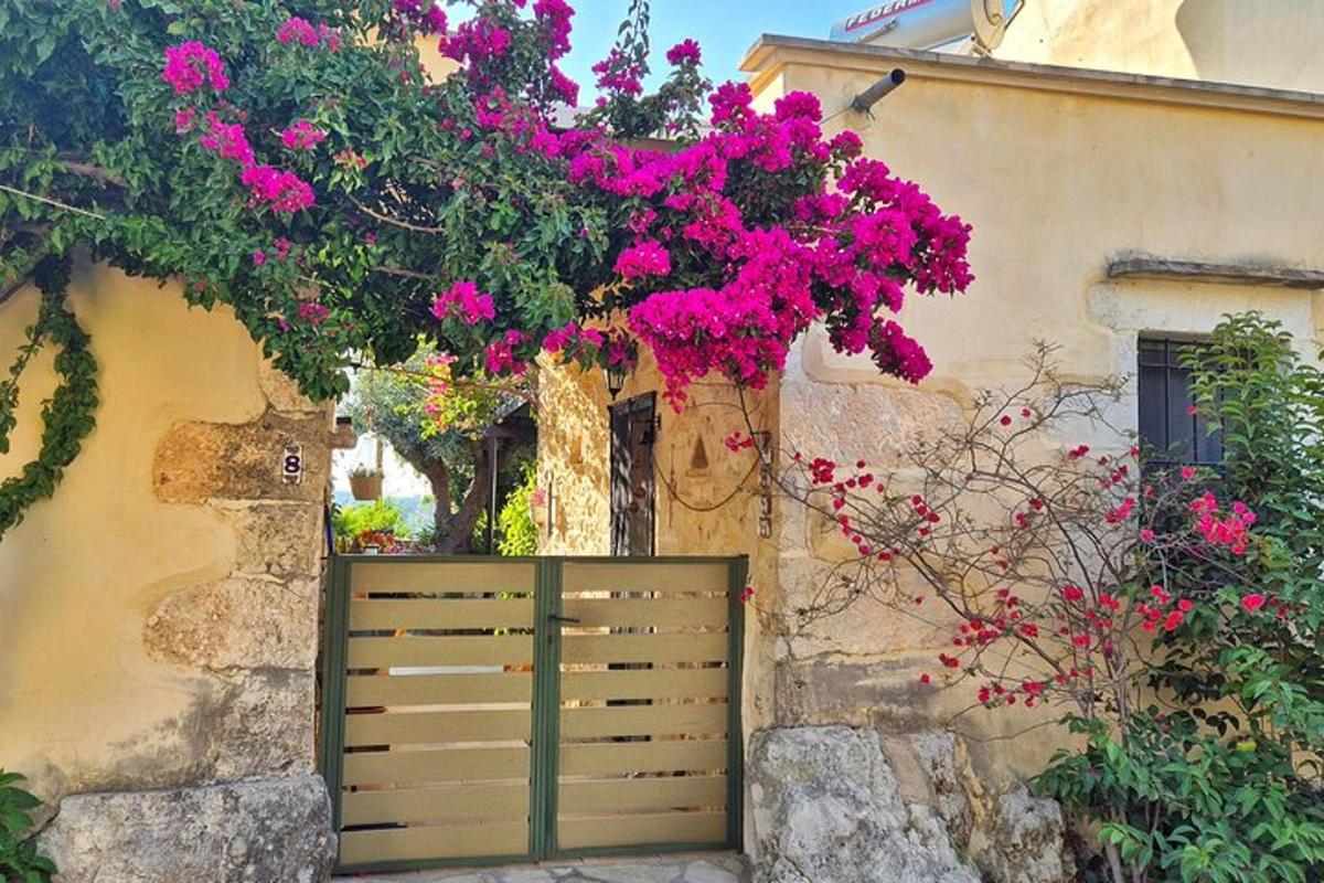 Μια ξύλινη πύλη μπροστά από ένα κτίριο με ροζ λουλούδια
