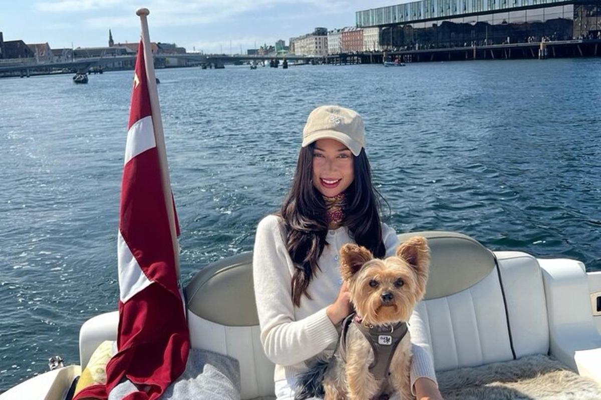 seorang wanita duduk di atas bot dengan seekor anjing kecil