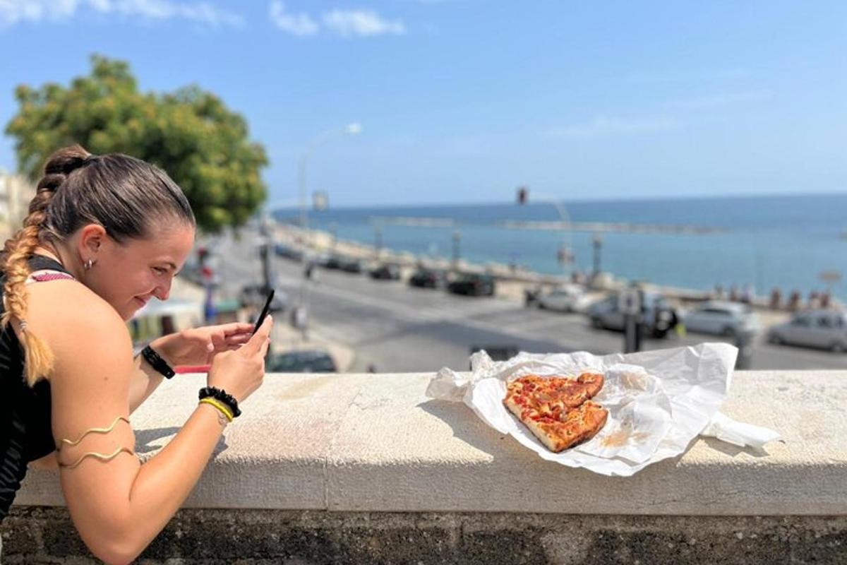 a woman looking at her cell phone with a slice of pizza