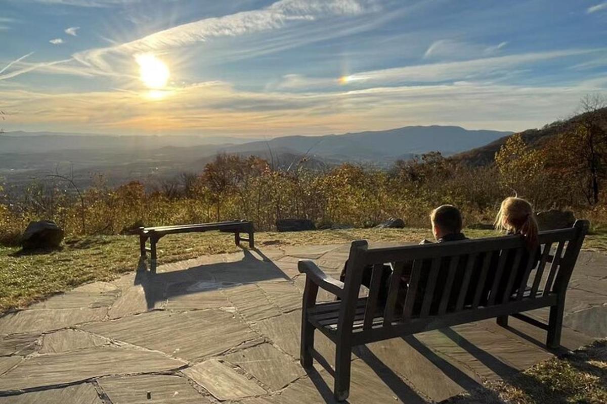 a man and woman sitting on a bench looking at the mountains