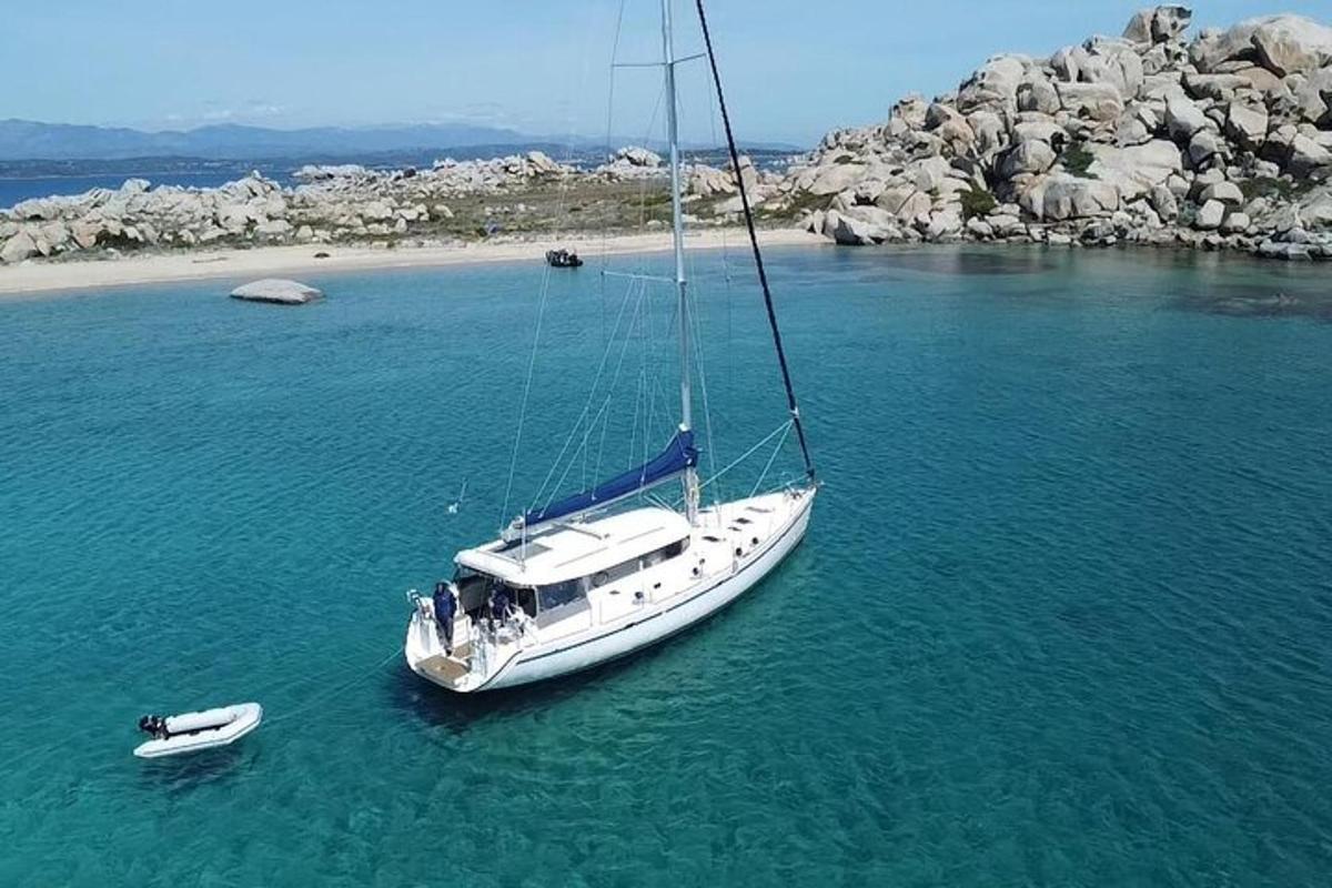 a white sailboat in the water next to a beach