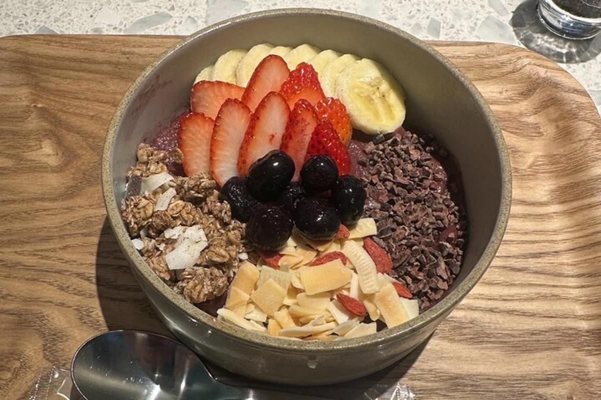 eine Schale mit Obst und Nüssen auf einem Holzschneidebrett