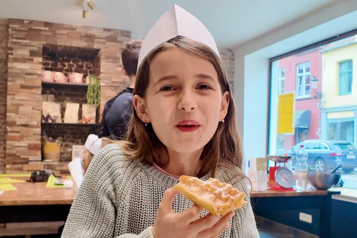 a young girl is eating a sandwich with a hat on her head