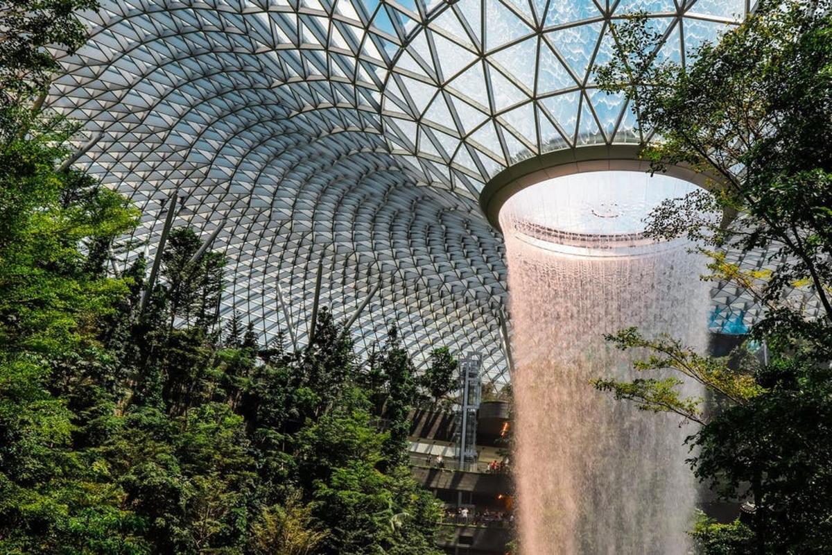 a waterfall in front of a large glass domed building