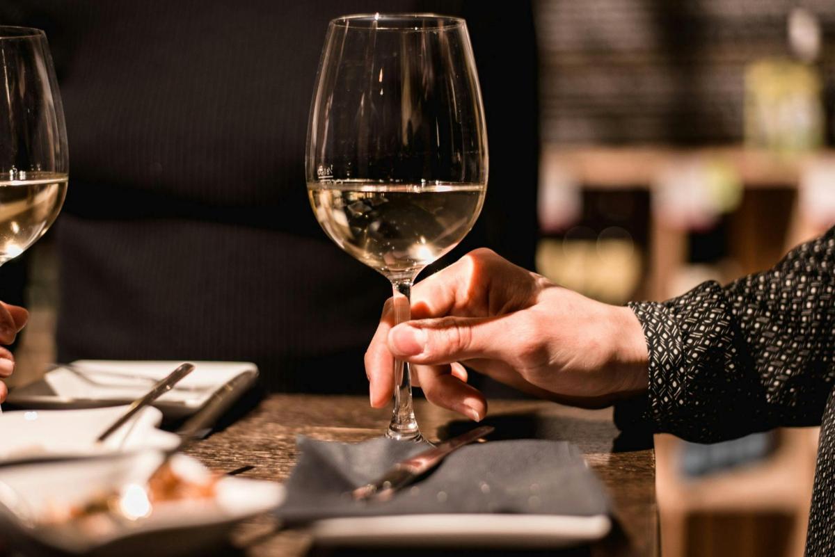 eine Person, die ein Glas Wein auf einem Tisch hält