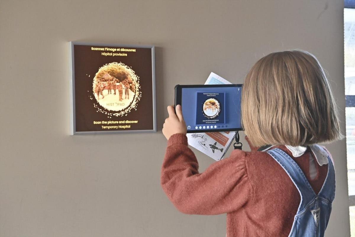 a woman taking a picture of a sign on a wall