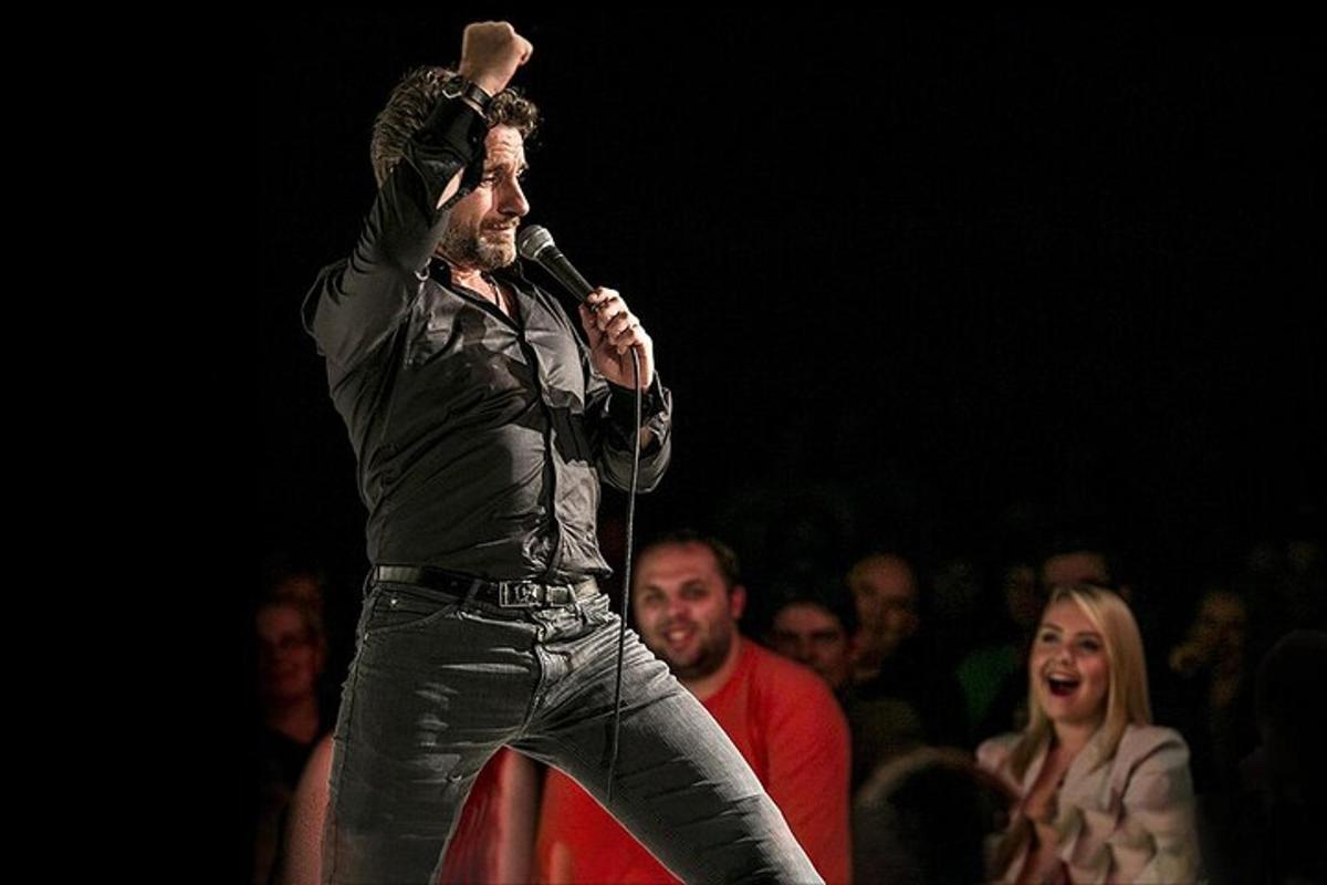 un uomo che canta in un microfono davanti a una folla