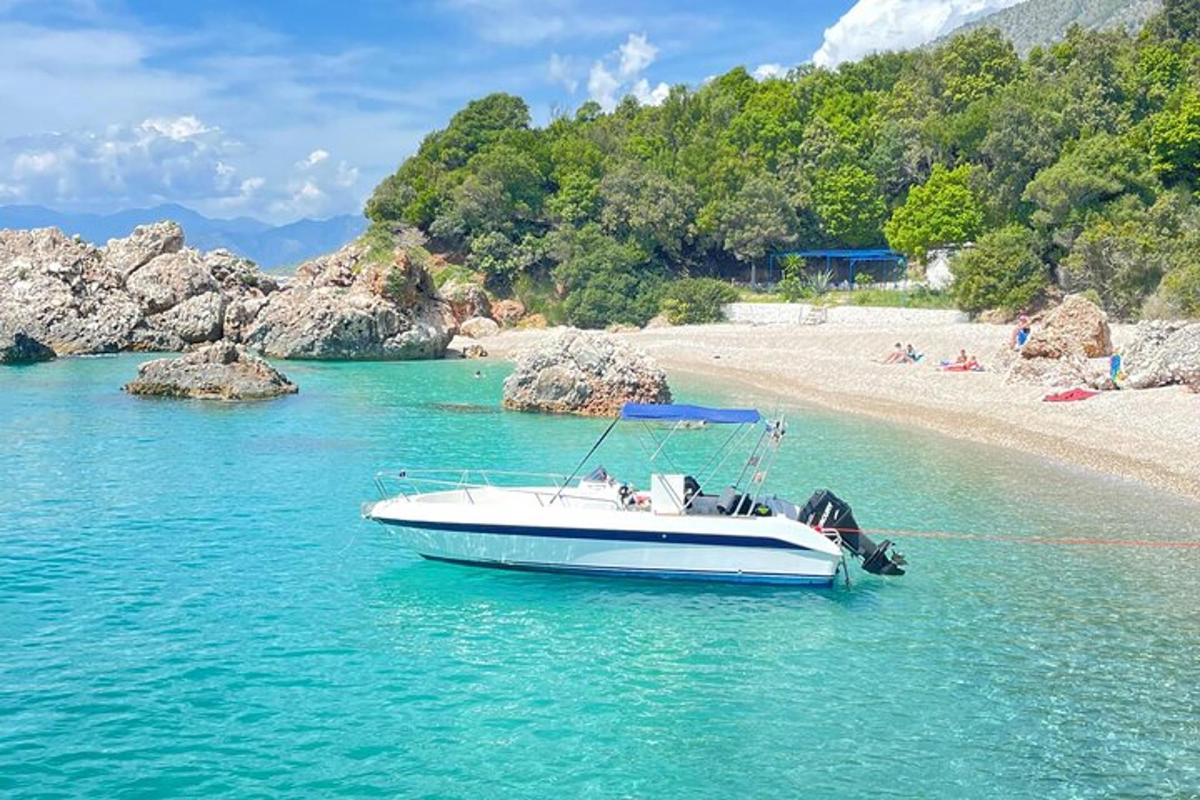 a white boat in the water next to a beach