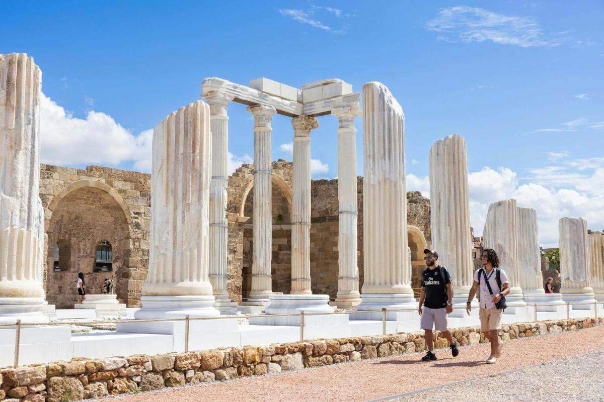 two people walking in front of a building with columns