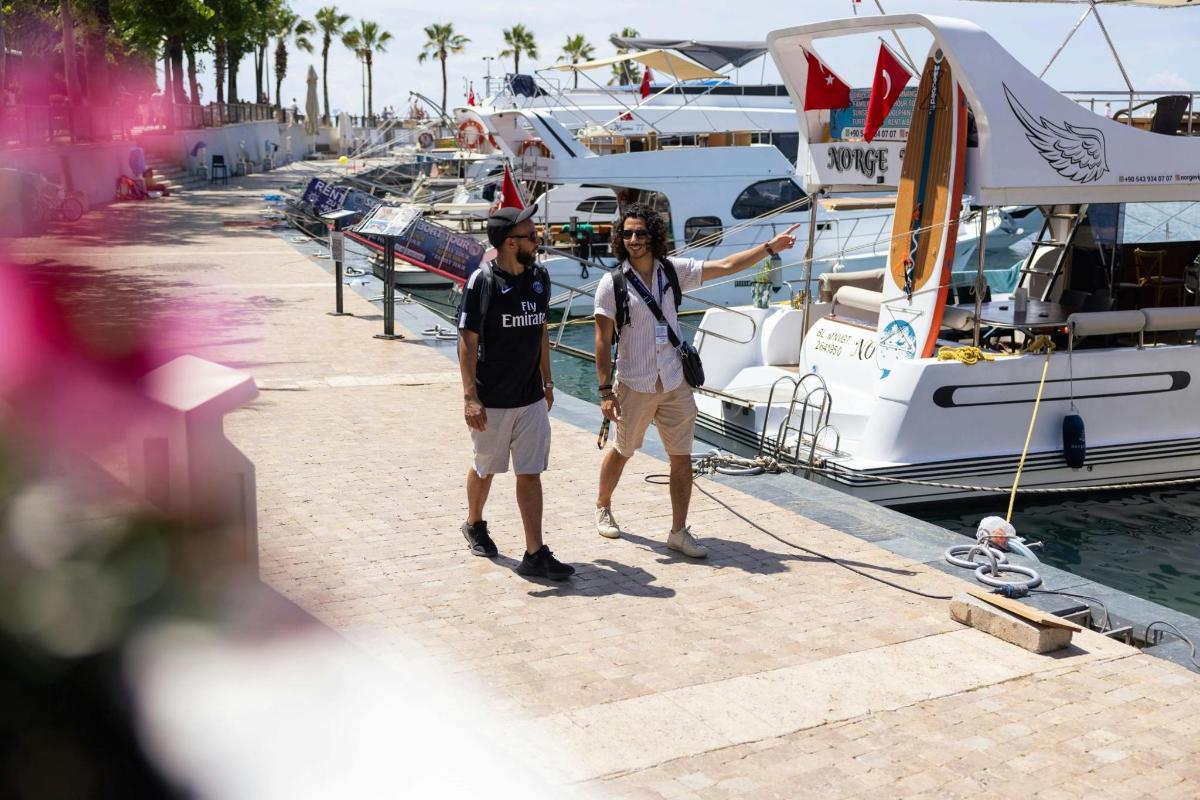 two men standing on a dock next to boats