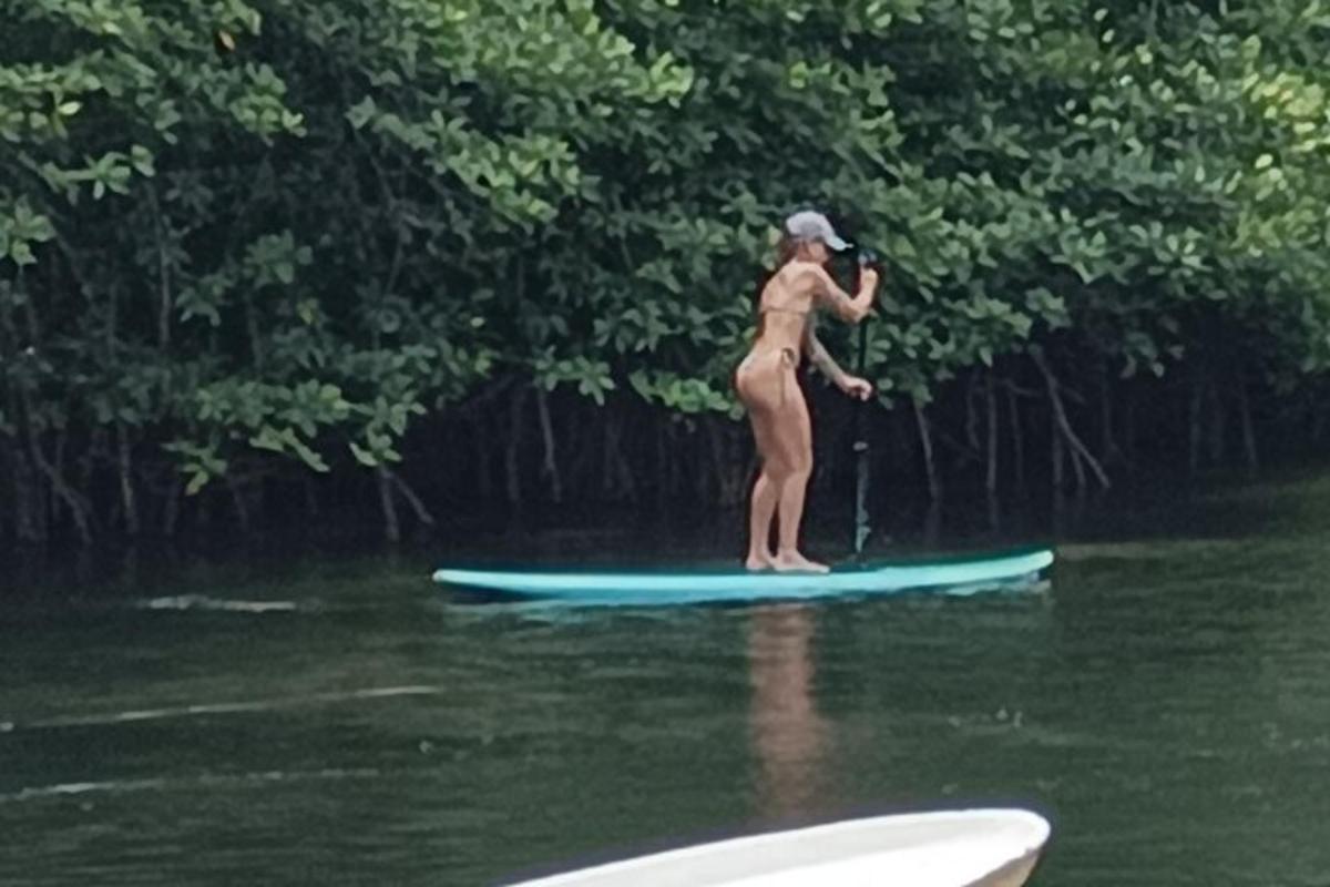 Una mujer parada sobre una tabla de remo en el agua