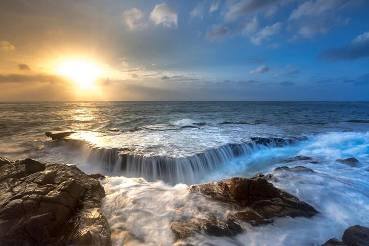 una cascata nell'oceano con il sole che tramonta