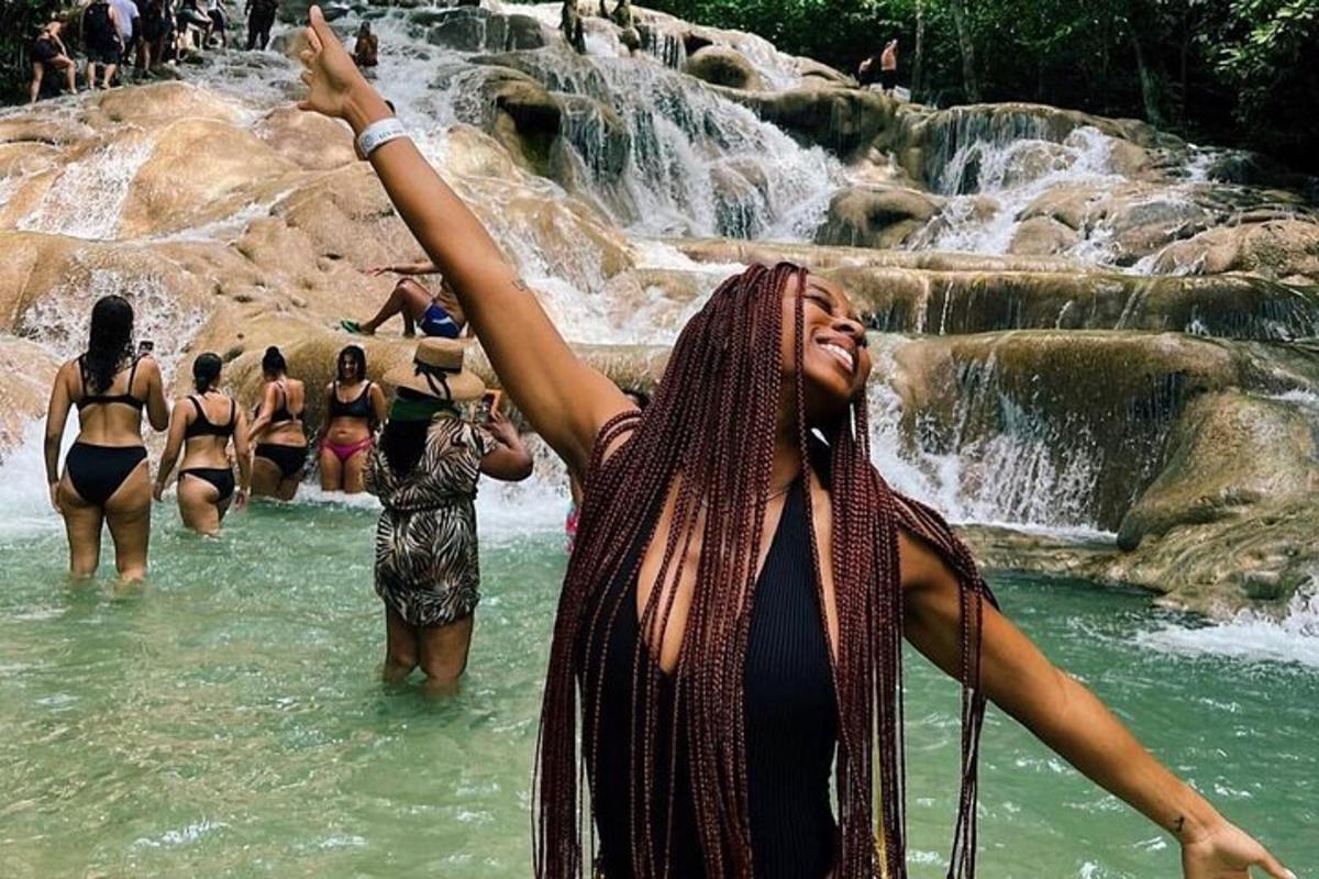 a woman standing in the water near a waterfall