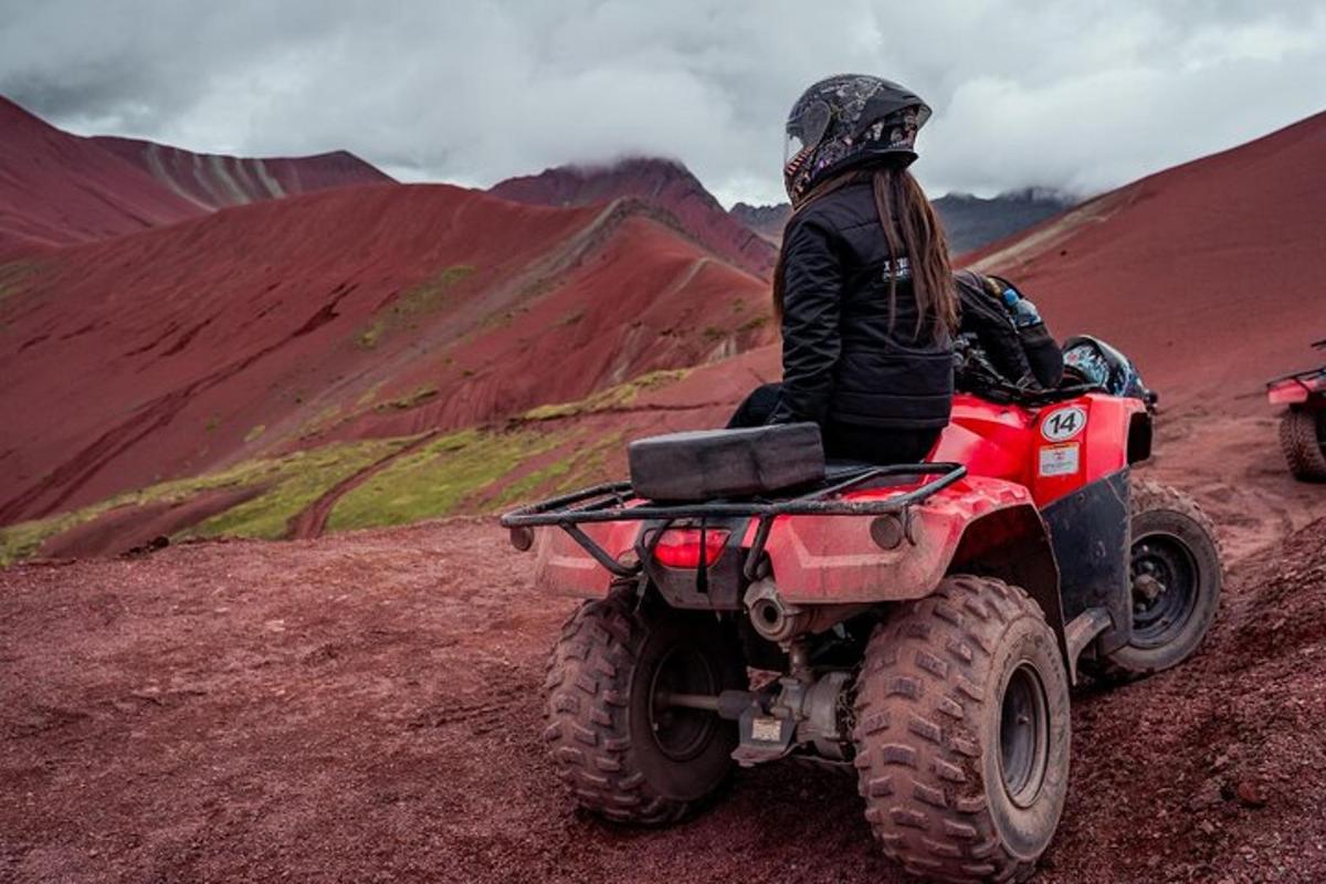 egy személy piros ATV-n vezet egy hegyen
