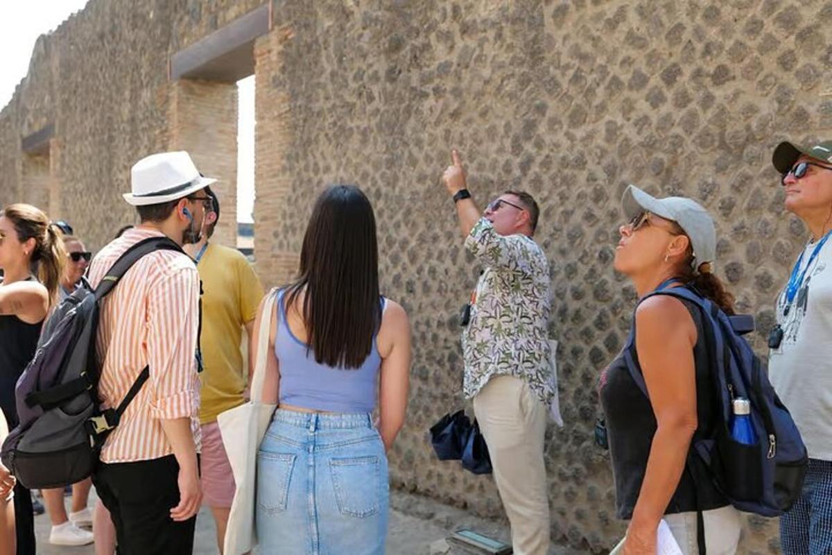 μια ομάδα ανθρώπων που στέκονται γύρω από έναν πέτρινο τοίχο