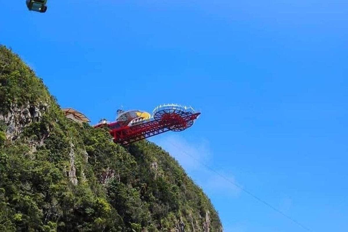 a roller coaster on a mountain with a blue sky