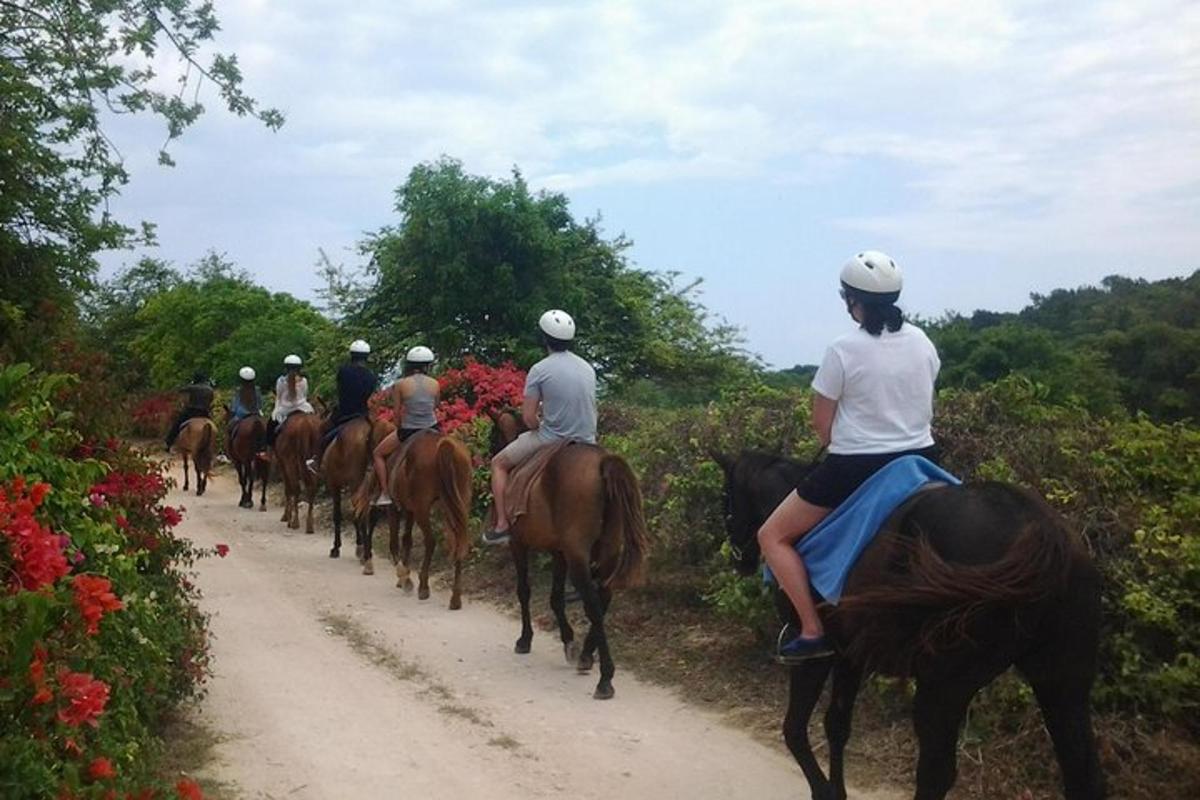 a group of people riding horses down a dirt road