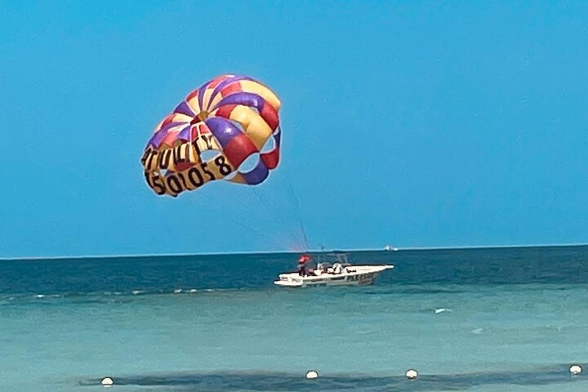 una persona che fa volare un aquilone sopra una barca nell'oceano