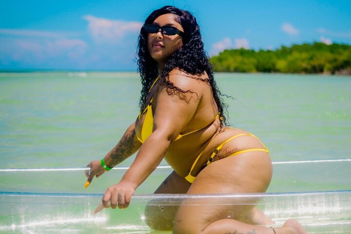 una donna in bikini giallo seduta su una tavola da surf in acqua