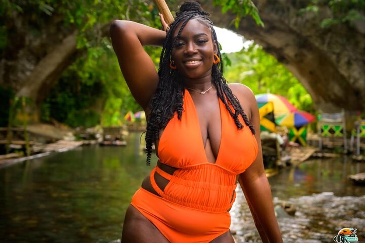 une femme en robe orange debout dans une rivière