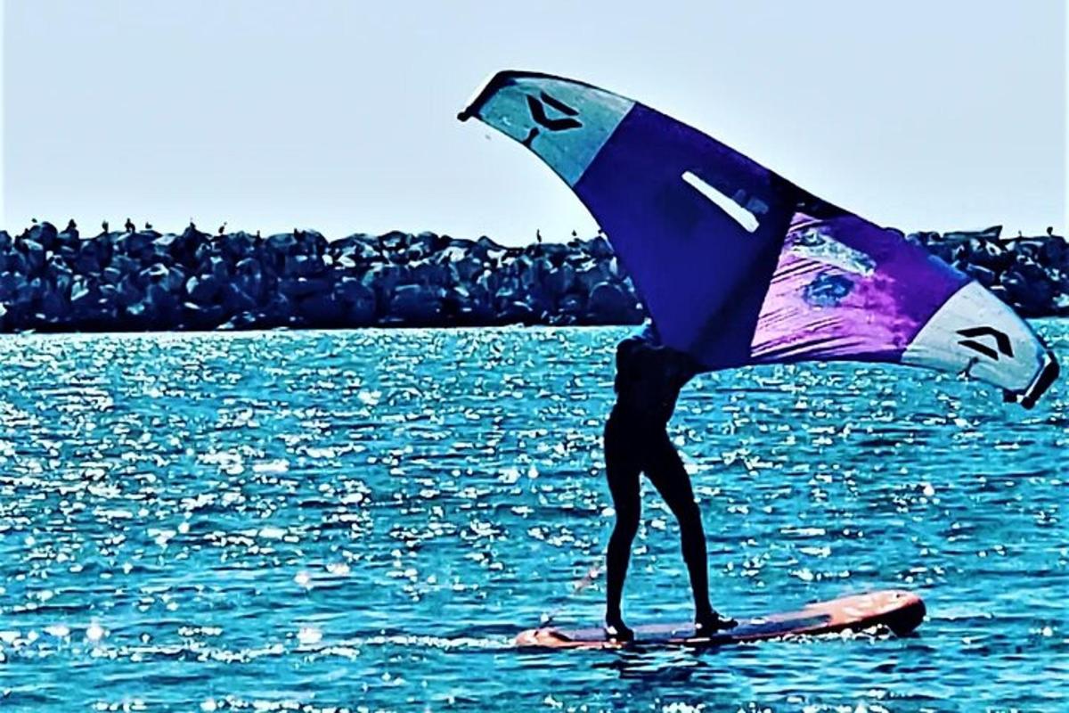 a person on a surfboard with a sail on the water