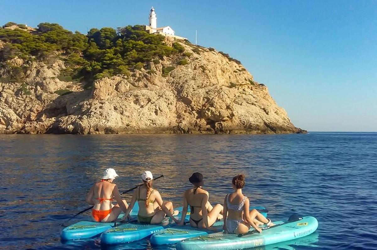 eine Gruppe von Menschen, die auf Kajaks im Wasser mit einem Leuchtturm sitzen