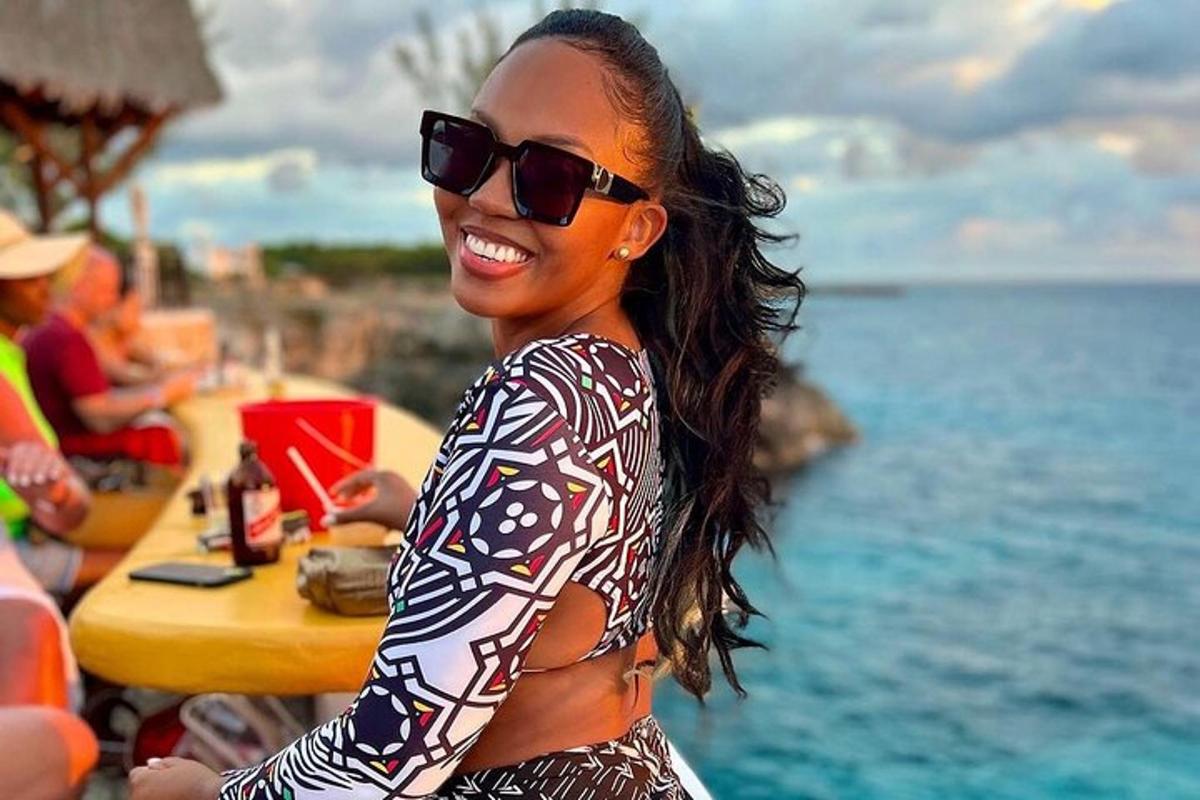 una donna che indossa occhiali da sole è in piedi su una spiaggia