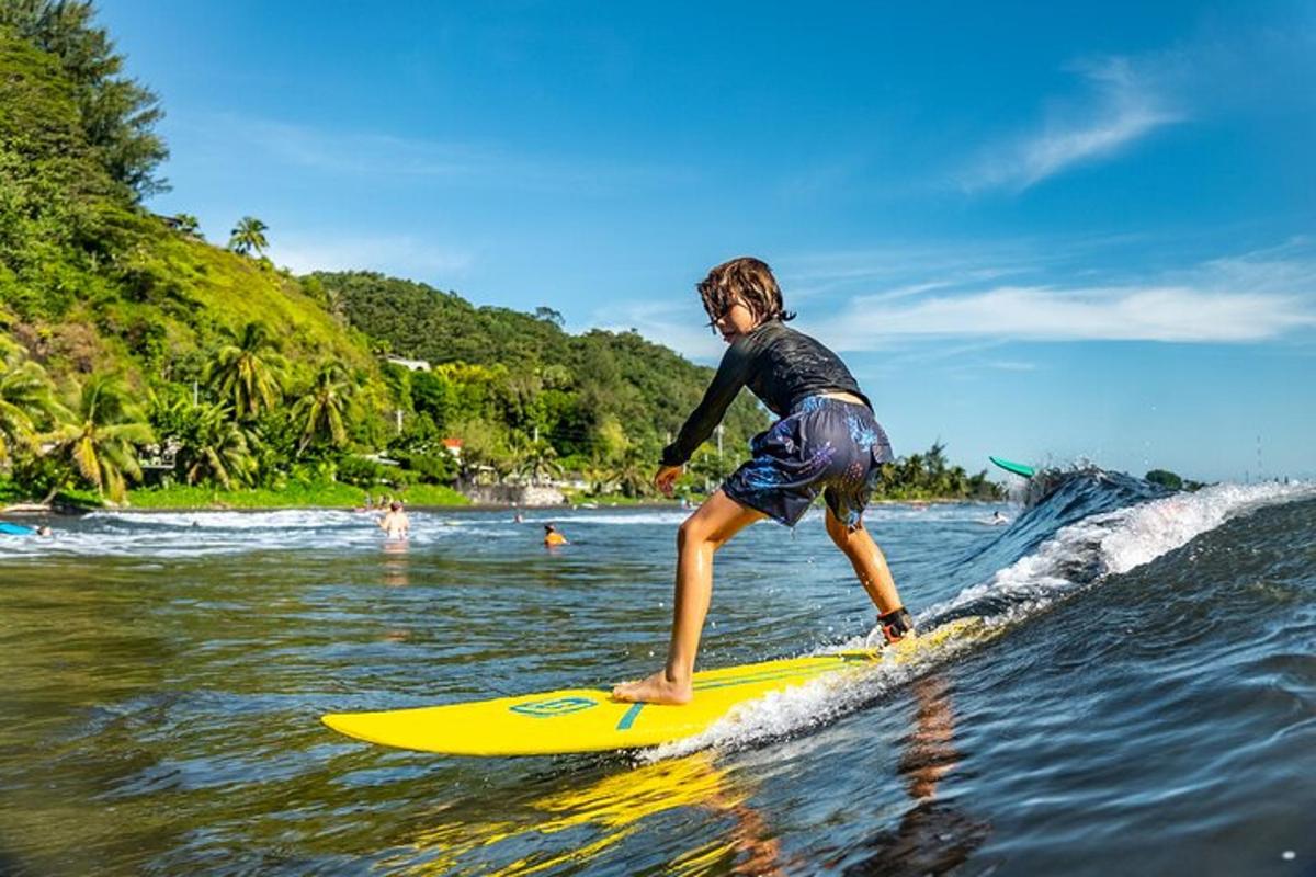 ein kleiner Junge, der auf einem gelben Surfbrett eine Welle reitet