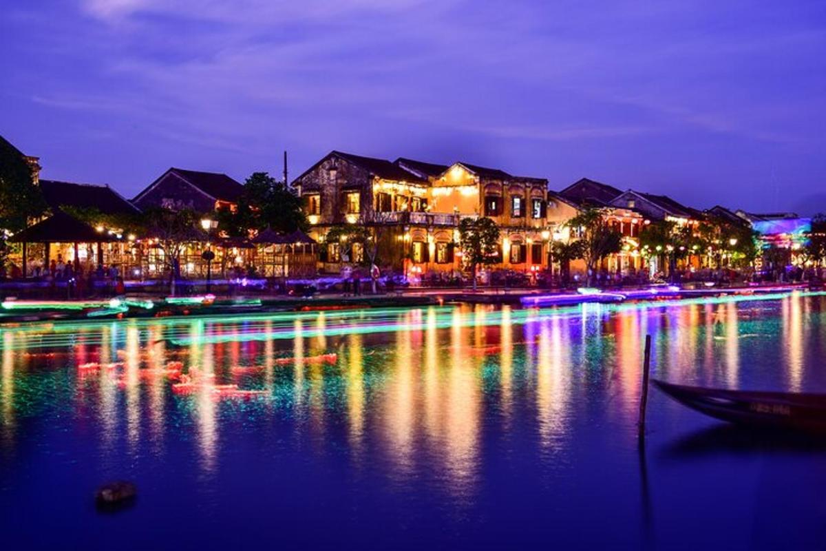 Un grupo de edificios con luces en el agua por la noche.