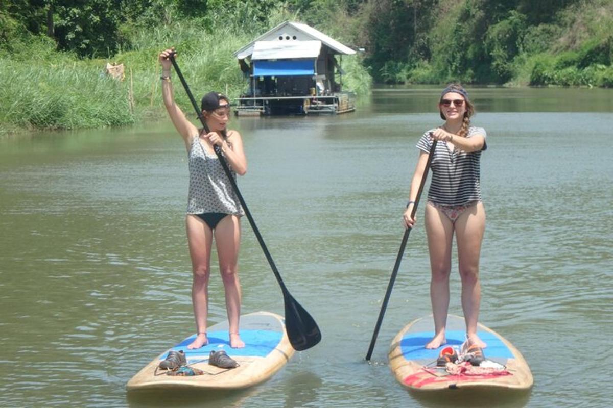 două fete stau pe plăci de paddle în apă