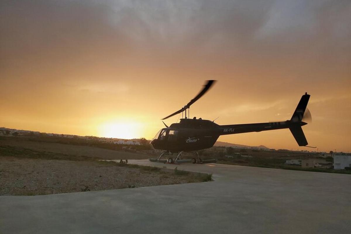 a helicopter sitting on a runway with the sunset in the background