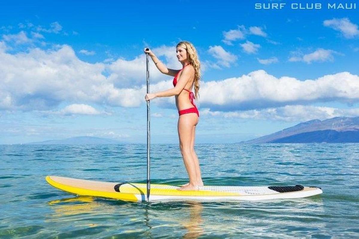 kona í bikiníi stendur á standandi brettabáti