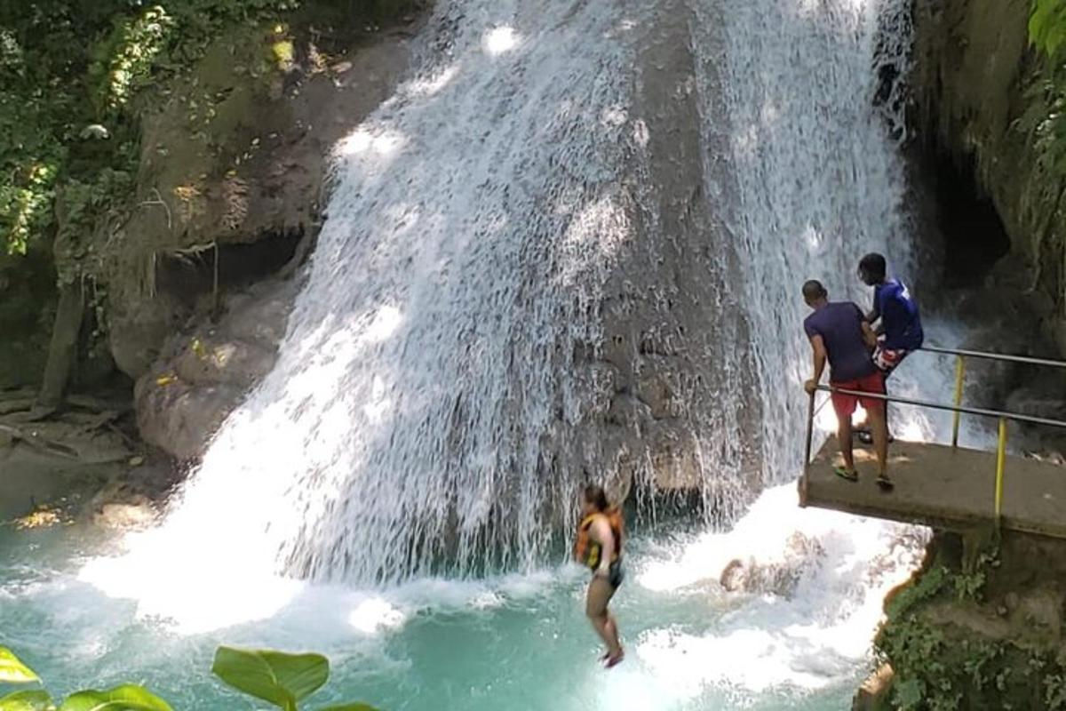 sekumpulan orang berdiri di dalam air terjun