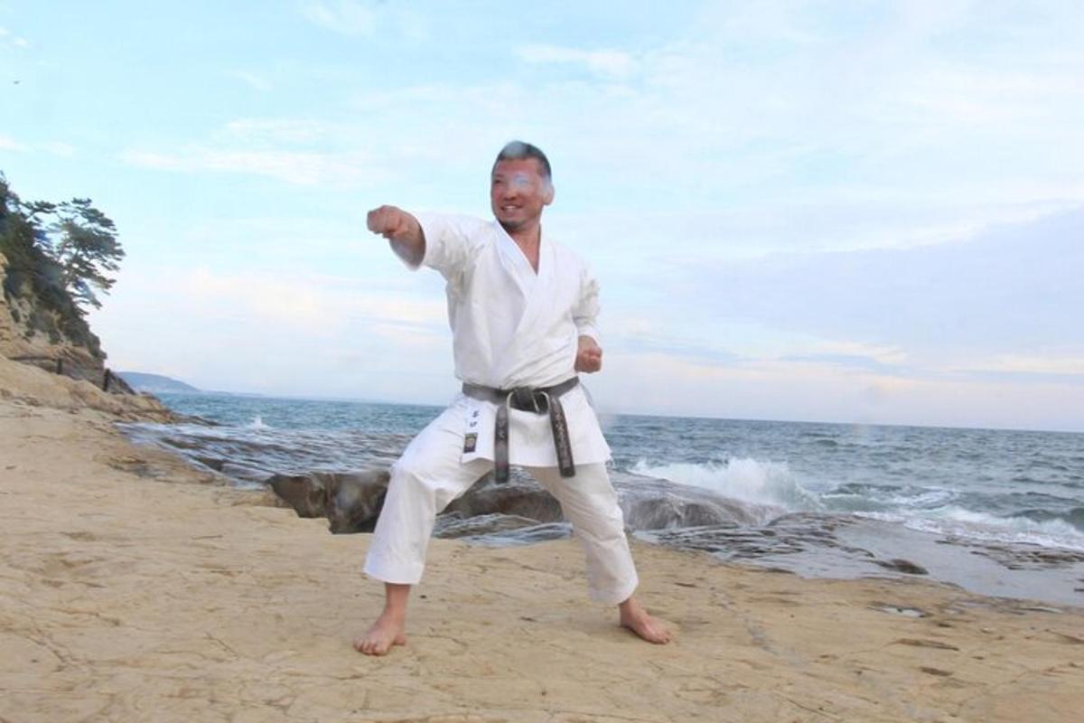 Maður í hvítum kimono stendur á ströndinni