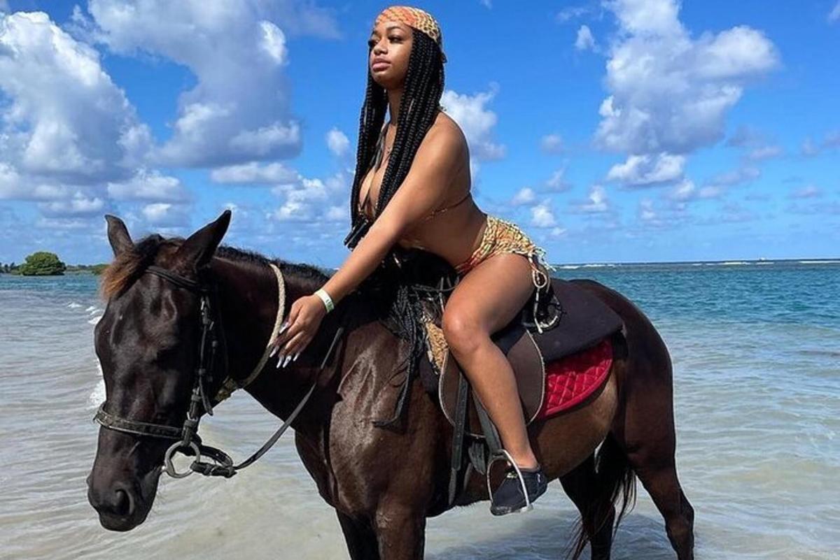 una mujer en bikini montando a caballo en la playa