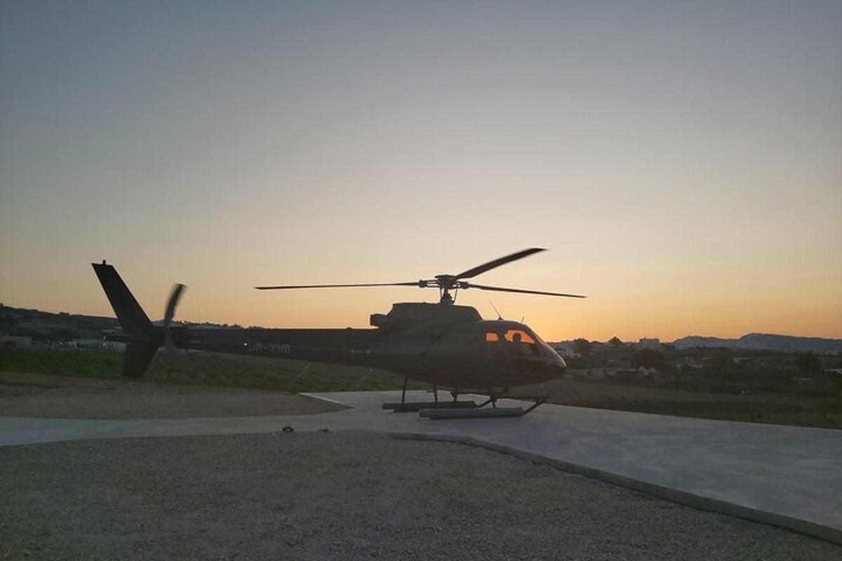helikopters sēž uz skrejceļa saulrietā