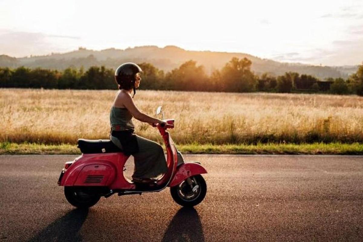 una donna che guida uno scooter rosa sulla strada