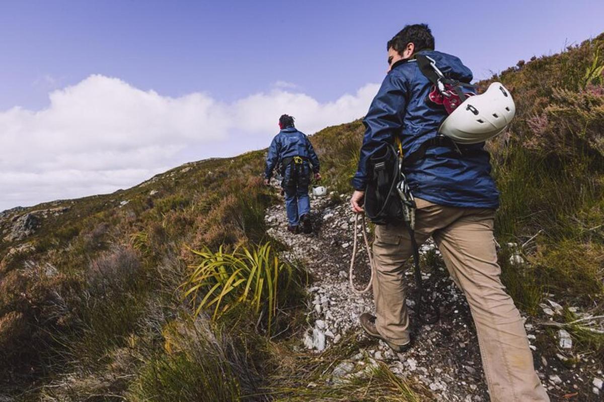 two people walking up a hill on a trail