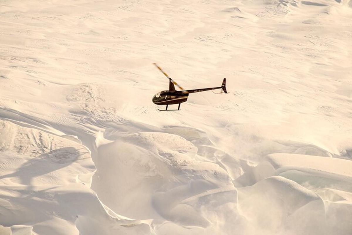 sebuah helikopter terbang di atas gunung yang dilitupi salji