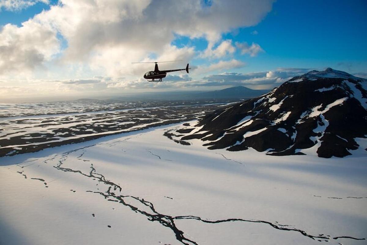 sebuah helikopter terbang di atas pantai dengan gunung