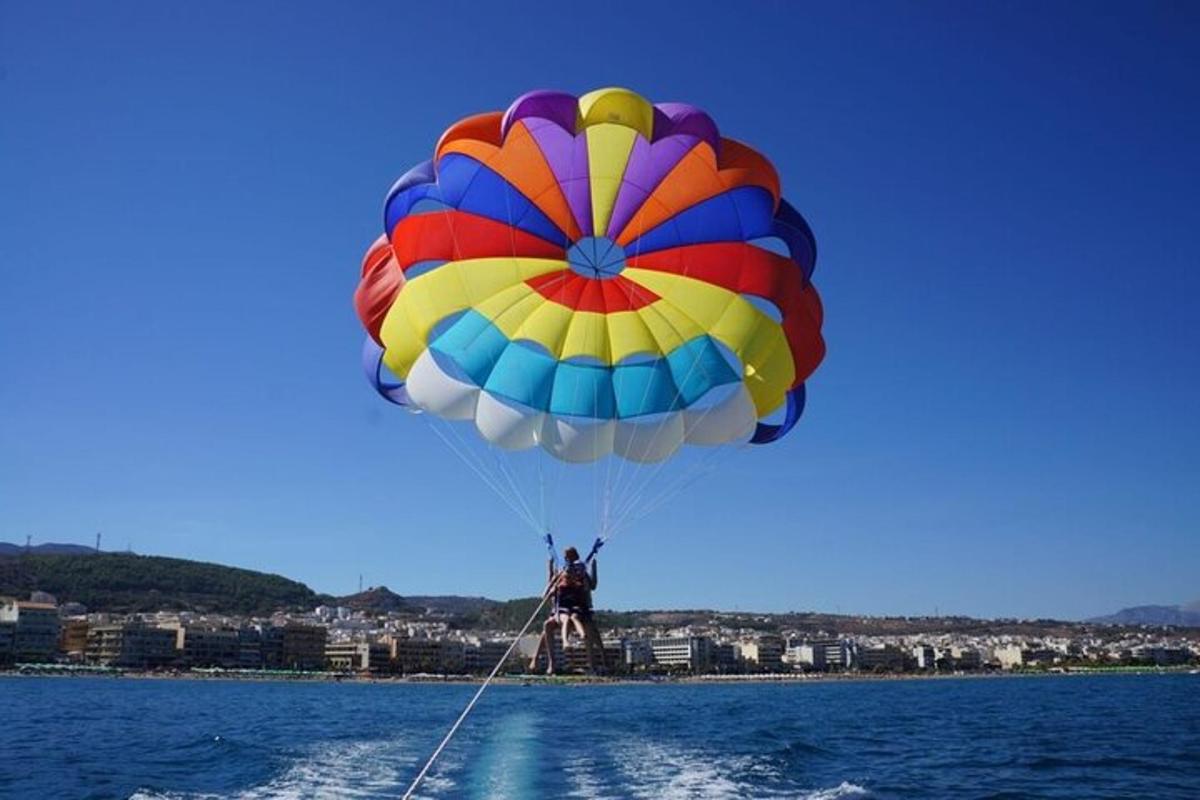 a person riding a colorful parachute over the water